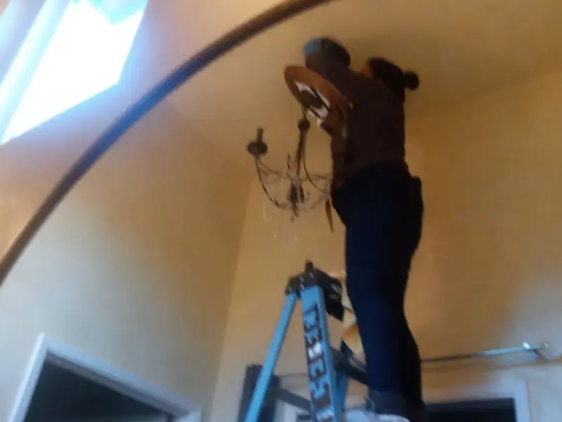 Electrician installing a chandelier in a Smithfield residence